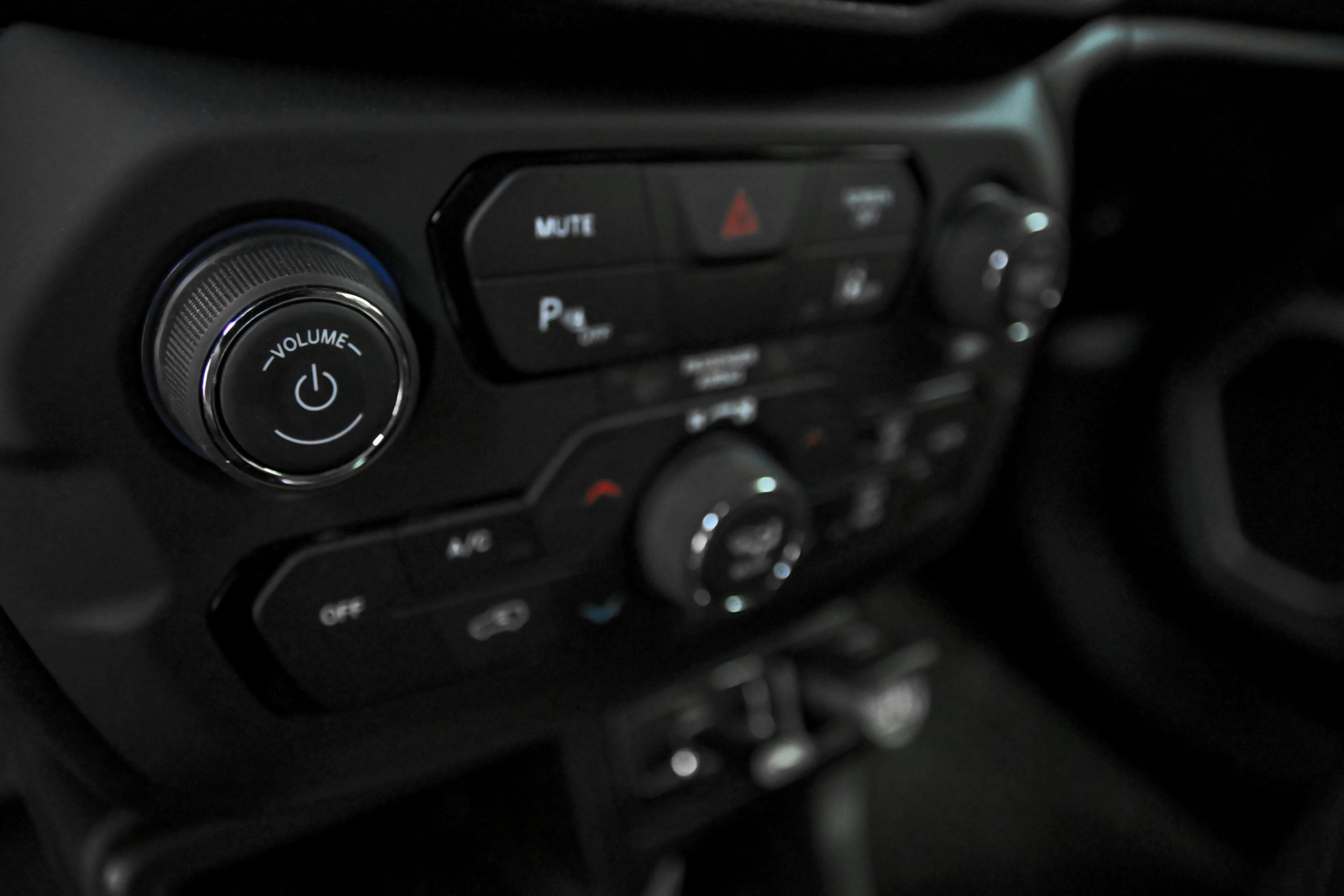 Detailed view of car dashboard featuring volume, AC, and power controls in a luxury vehicle.